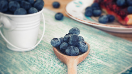 Close up of blueberries on wooden spoon with pie dessert