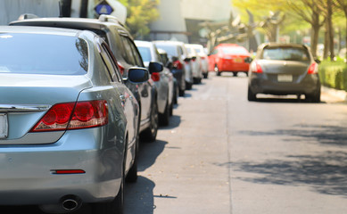 Naklejka premium Closeup of rear or back side of green blue car with other cars parking in outdoor parking area beside the street in bright sunny day. 