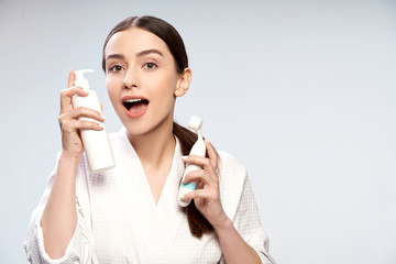 Charming young woman holding bottle of cosmetic cream and pore cleansing brush