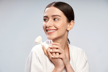 Charming young woman in white bathrobe holding pore cleansing brush