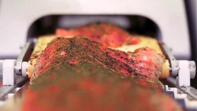 Gravlax (Salmon) being sliced and handled in a machine.