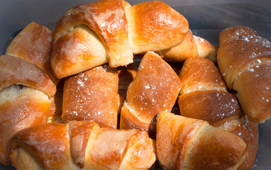 Homemade croissants with cherries in a plastic container isolated on wooden background.
