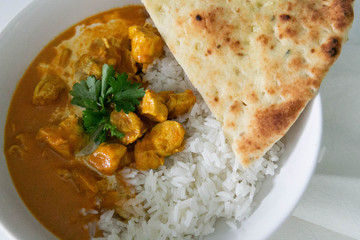 Bowl of Indian Butter Chicken with Jasmine Rice, Homemade Naan, and Cilantro, White Background, Closeup