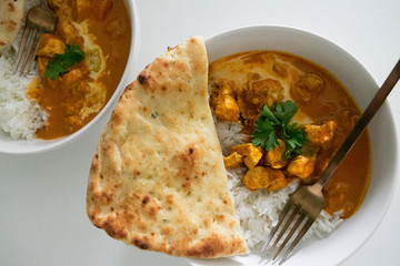 Two Bowls of Indian Butter Chicken and Jasmine Rice with Homemade Naan