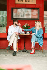 Happy beautiful couple is sitting in outdoor cafe - obrazy, fototapety, plakaty