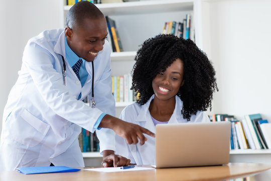 Laughing african american male doctor and nurse working at computer