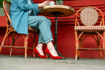 Happy woman in red shoes sitting in cafe