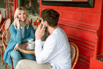 Smiling couple using smartphones in cafe outdoors