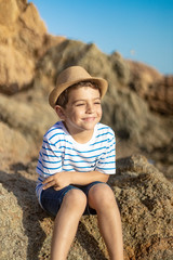Portrait of a cute child sitting on a rocks near the sea