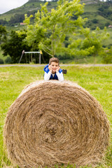 Naklejka na ściany i meble Cute boy on top of a straw bale