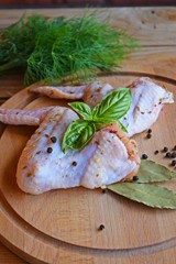 Raw chicken wings with spices and herbs on a wooden Board for grilling.