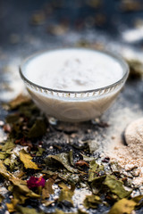 Neem or Indian Lilac face mask on the black wooden surface for acne and scars consisting of gram flour, neem paste, and some curd.