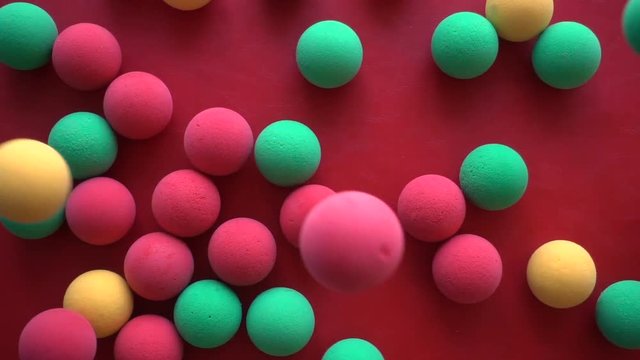 Colorful sponge balls on a red background, Slow motion