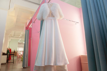 Wedding dress hangs on the wall in salon dressing room