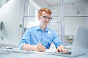 Fototapeta premium Young successful designer looking at curious online stuff on laptop display