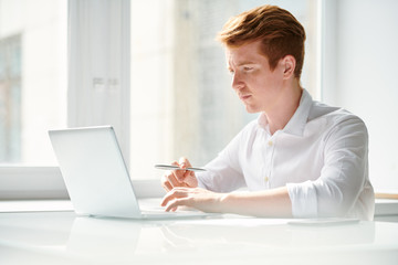 Fototapeta premium Pensive student working over educational project or preparing home assignment