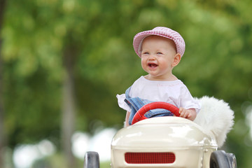 lachendes kleines Mädchen im Spielzeugauto