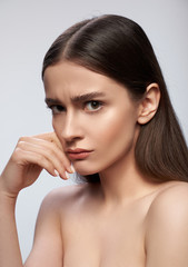 Upset woman standing against light gray background in studio