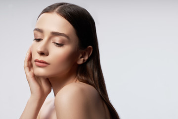 Charming young lady with natural makeup keeping hand near head