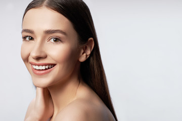 Beautiful young woman with natural makeup touching her neck