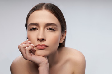 Pretty young woman is keeping hand on her chin