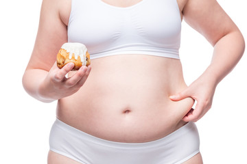fat woman with calorie muffin in her hand squeezes belly closeup