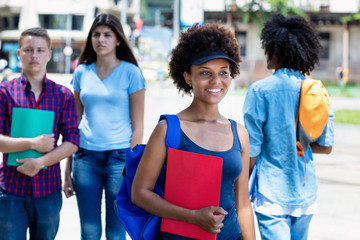 African american young adult woman with students walking in city