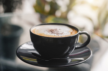 close up modern hot black coffee the cappuccino on dark background with coffee bubble foam pattern and texture in black cup looking and feel so delicious on glasses table in coffee shop.