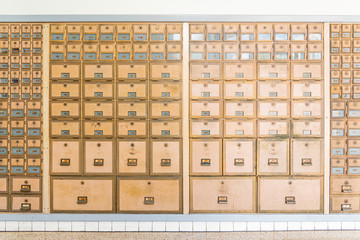Rows of mid-century modern design post office mailboxes in brass metal.