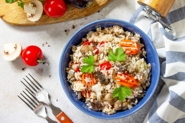 Diet menu. Healthy food. Vegetarian vegetable mushrooms pilaf. Rice with eggplant and mushrooms on stone table. Top view flat lay.