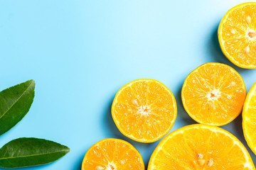 Sliced orange fruits with leaves on blue background, flat design