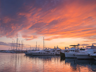 Yachts under orange clouds in harbor in Greece