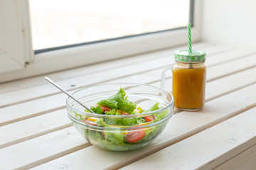 Vegetable salad and fruit smoothies lie on a white windowsill. Concept of healthy lifestyle physical activity and proper nutrition.