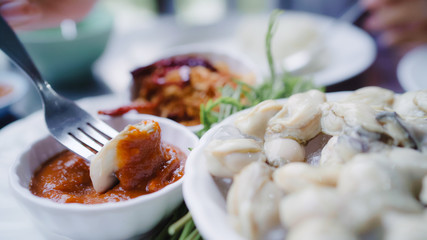 Young Asian woman eating oyster seafood in restaurant, teenager female feeling happy eating food. Women eating seafood concept.