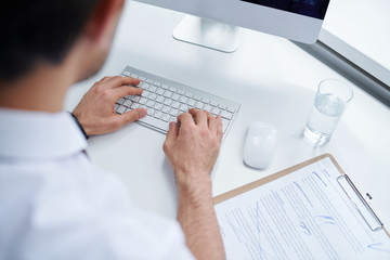 Hands of young analyst or broker touching keys of computer keypad