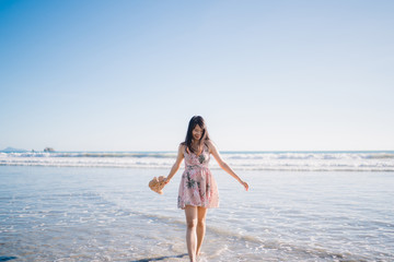 Fototapeta na wymiar Young Asian woman walking on beach. Beautiful female happy relax walking on beach near sea when sunset in evening. Lifestyle women travel on beach concept.