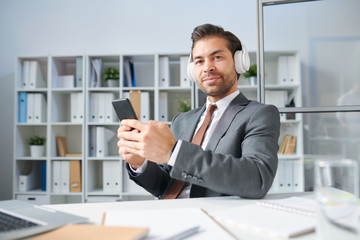 Fototapeta premium Confident businessman in headphones listening to music from playlist