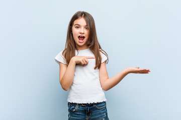 Cute girl excited holding a copy space on palm.