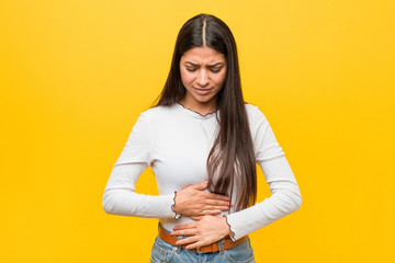Young pretty arab woman against a yellow background sick, suffering from stomachache, painful...