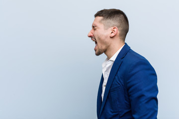 Young business caucasian man shouting towards a copy space