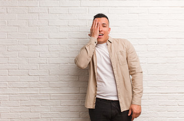 Young latin man shouting happy and covering face with hand