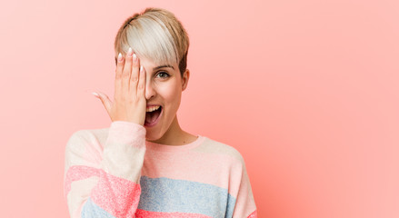Young natural curvy woman having fun covering half of face with palm.