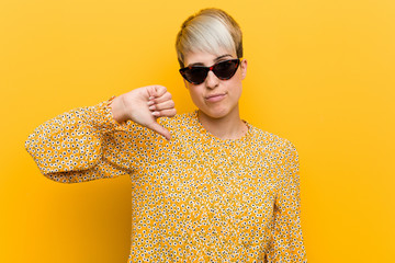 Young curvy woman wearing a floral summer clothes showing a dislike gesture, thumbs down....