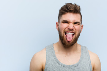 Obraz premium Young handsome fitness man funny and friendly sticking out him tongue.