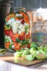 Hand made rural pickled vegetables food for the winter with carrots, peppers, paprika, cauliflower, green tomatoes and celery in a big jar.