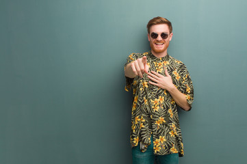 Young redhead man wearing exotic summer clothes dreams of achieving goals and purposes