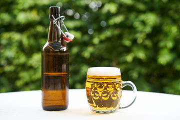 Craft made filtered pilsner type czech beer from small local brewery in traditional czech mug and beer bottles served on the table outside in beer garden in summer sunny evening as refreshing drink.
