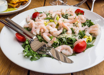 Fresh salad plate with shrimp, avocado, tomato and mixed greens (arugula, mesclun, mache) on wooden background close up. Healthy food. Clean eating.