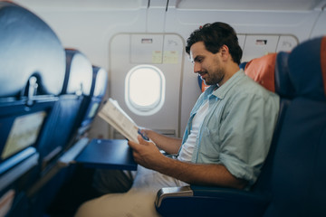 Obraz premium The guy flies in an airplane with a magazine in his hands