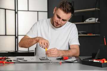 Technician repairing mobile phone at table in workshop